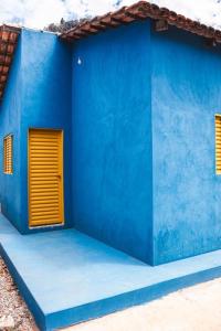 a blue building with a yellow door on it at Chalé Azul Aurora in Manhã +5 photos