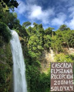 a waterfall in front of a sign next to a waterfall at Cascada Elysiana in Platanillo
