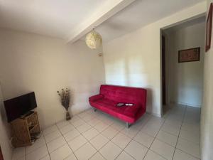 un divano rosso in un soggiorno con TV di La petite campagne a Le Moule