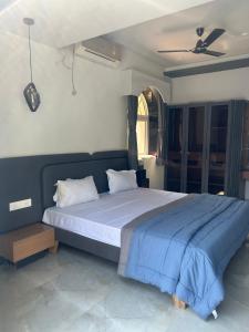 a bedroom with a large bed with a blue blanket at Atishay Villa I 4BHK I Pure veg I Pvt Pool & lawn in Lonavala +25 photos