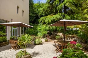 une terrasse avec une table, des chaises et des parasols dans l'établissement ibis Lannion, à Lannion