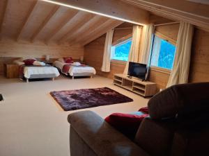 a room with two beds and a couch and a television at Chalet la Fiolaz in Châtel