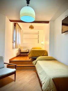 een kamer met 2 bedden en een stoel en een lamp bij Hotel Cervantes in Villa Gesell