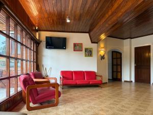 een woonkamer met 2 rode stoelen en een flatscreen-tv bij Hotel Cervantes in Villa Gesell