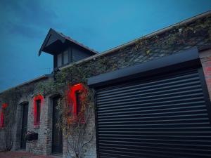 a garage door on the side of a building with red windows at L' Instant Se Crée in Oignies