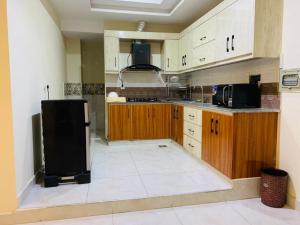 a kitchen with a black refrigerator and wooden cabinets at Pavilion 99 Serenity Appartment 2bhk in Rawalpindi