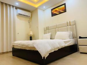 a bedroom with a large bed with white sheets at Pavilion 99 Serenity Appartment 2bhk in Rawalpindi