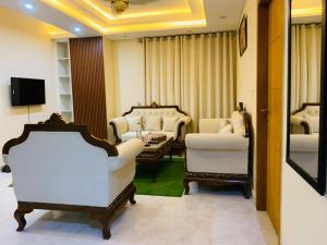 a living room with white chairs and a table at Pavilion 99 Serenity Appartment 2bhk in Rawalpindi