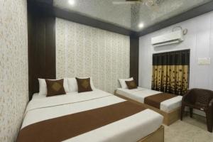 a bedroom with two beds and a chair at HOTEL SHIVAYY MAJESTIC - BHU Sundarpur Road 3km from KASHI VISHWANATH TEMPLE in Varanasi