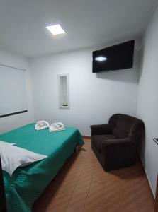 a room with a bed and a couch and a flat screen tv at Hotel Portal Norte Neuquino in Chos Malal