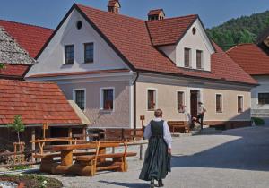 a woman in a dress standing in front of a building at Notranjska hiša - traditional country house, close to the world attraction Cerknica lake in Begunje pri Cerknici