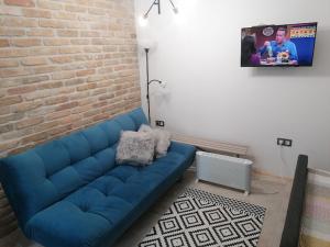 a blue couch in a living room with a brick wall at Ide-Odú Apartman in Baja
