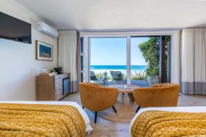 ein Schlafzimmer mit zwei Betten und einem Tisch mit Blick auf das Meer in der Unterkunft Dune Beach House in Wilderness
