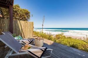 eine Terrasse mit einem Tisch und Stühlen am Strand in der Unterkunft Dune Beach House in Wilderness