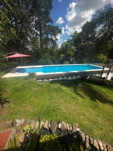 een groot zwembad in een tuin naast een veld bij Jacaranda 3 in Agua de Oro