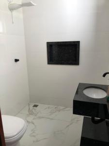 een witte badkamer met een toilet en een wastafel bij Apartamento Piúma in Piúma +7 foto's