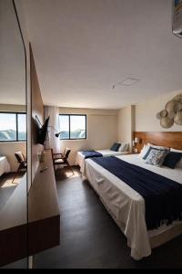 een hotelkamer met 2 bedden en 2 stoelen bij Suítes Natal Plaza 4 Estrelas - Vista Mar - Ponta Negra in Natal +35 foto's