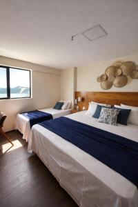 een hotelkamer met twee bedden en een raam bij Suítes Natal Plaza 4 Estrelas - Vista Mar - Ponta Negra in Natal