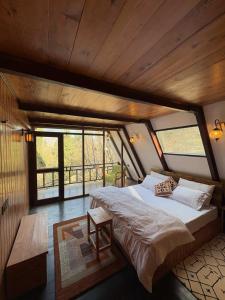 een slaapkamer met een groot bed in een kamer met ramen bij Mysa, A-frame cottage in Shirir