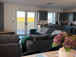 a living room with a couch and a kitchen at Black Dub Cottage in Allonby