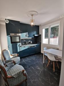 une cuisine avec des armoires bleues et une table et des chaises dans l'établissement Independent studio 12 min from Paris, à Deuil-la-Barre