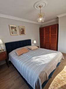 une chambre avec un grand lit bleu avec un lustre dans l'établissement Independent studio 12 min from Paris, à Deuil-la-Barre