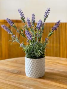 a white vase with purple flowers sitting on a table at Ferienwohnung "Traumsuite am Tegernsee" in Tegernsee