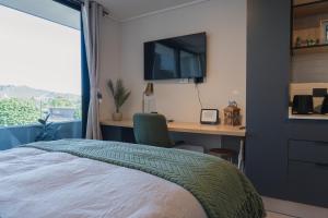 a bedroom with a bed and a desk and a television at Suite Compacta y Elegante in Temuco