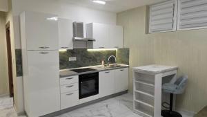 una cucina con mobili bianchi e un lavandino di Green Apartman a Veternik