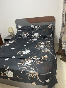 a bed with a black comforter with flowers on it at At your home in Conakry in Conakry