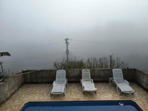 - deux chaises longues et une piscine en face d'une maison dans l'établissement CHÁCARA dos CHEIROS, à Atibaia