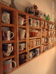 une étagère remplie de tasses et d'assiettes sur un mur dans l'établissement CHÁCARA dos CHEIROS, à Atibaia