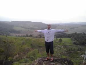 un homme debout sur un rocher, les bras tendus dans l'établissement CHÁCARA dos CHEIROS, à Atibaia
