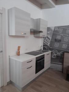 a white kitchen with a sink and a stove at ROCKEFELLER SUIT Apartment in Sassari +3 photos