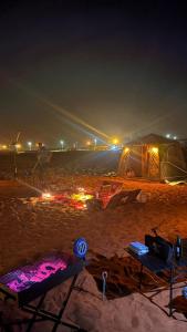 een strand met een tent en een tafel in het zand 's nachts bij ArabTribe in Margham +2 foto's