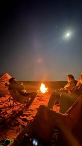 een groep mensen die rond een vuur op een strand zitten bij ArabTribe in Margham