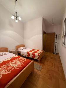 een slaapkamer met twee bedden en een houten vloer bij Vila Žuta in Bar