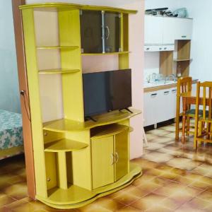 a yellow entertainment center with a television in a kitchen at Casa para até 6 pessoas, próxima do mar in Cidreira