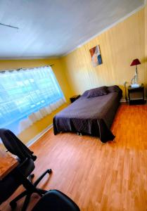 a bedroom with a bed and a desk and a window at Hostel Notro Valdivia in Valdivia