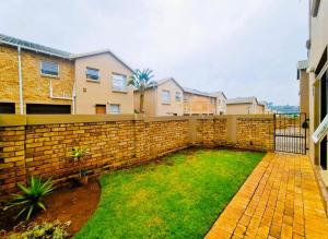 a backyard with a brick wall and a yard at Blissfulnest stay two in Roodepoort