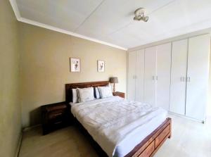 a bedroom with a large bed with white sheets at Blissfulnest stay two in Roodepoort