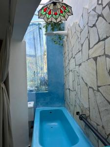 bagno con vasca blu e parete in pietra di Chalé Vista Mar a Ilhabela