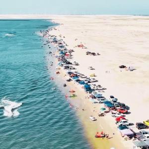 a beach with a bunch of cars and umbrellas at Casa para até 6 pessoas, próxima do mar in Cidreira +9 photos