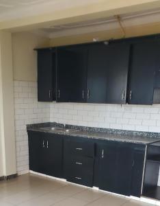a kitchen with black cabinets and a sink at EasyStay in Kampala