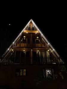 een groot houten huis met een terras in de nacht bij Mysa, A-frame cottage in Shirir +14 foto's