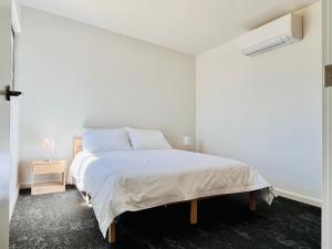 ein weißes Schlafzimmer mit einem Bett und einem Nachttisch in der Unterkunft Castlemaine Short Stays in Castlemaine