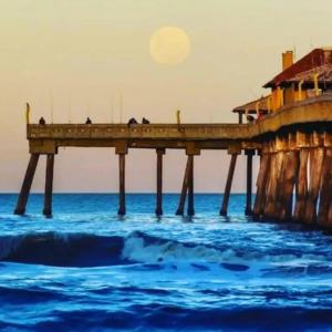 a pier in the ocean with the moon in the sky at Casa para até 6 pessoas, próxima do mar in Cidreira