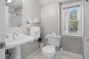 a white bathroom with a toilet and a sink at Duplex Rooftop at MIT Kendall Sq - 2 FREE Parking in Cambridge +31 photos