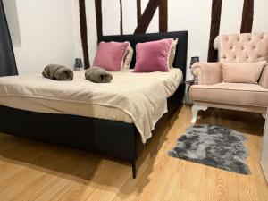 une chambre avec un lit avec des oreillers roses et une chaise dans l'établissement Le cocon chic, à Montereau-faut-Yonne