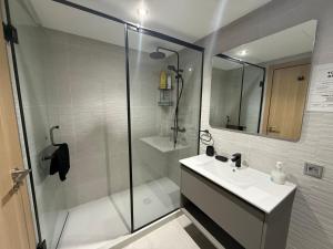 a white bathroom with a shower and a sink at Hilton View Tower Residency Apartment Tanger Partial Sea View in Tangier +14 photos